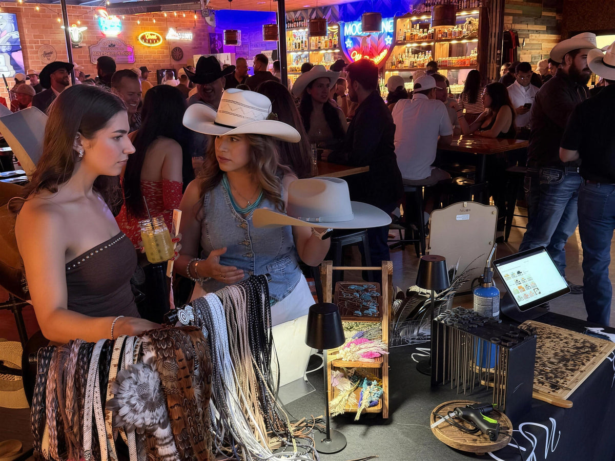 Guests customizing cowboy hats at a Wild Pony pop up hat bar in a busy San Antonio bar
