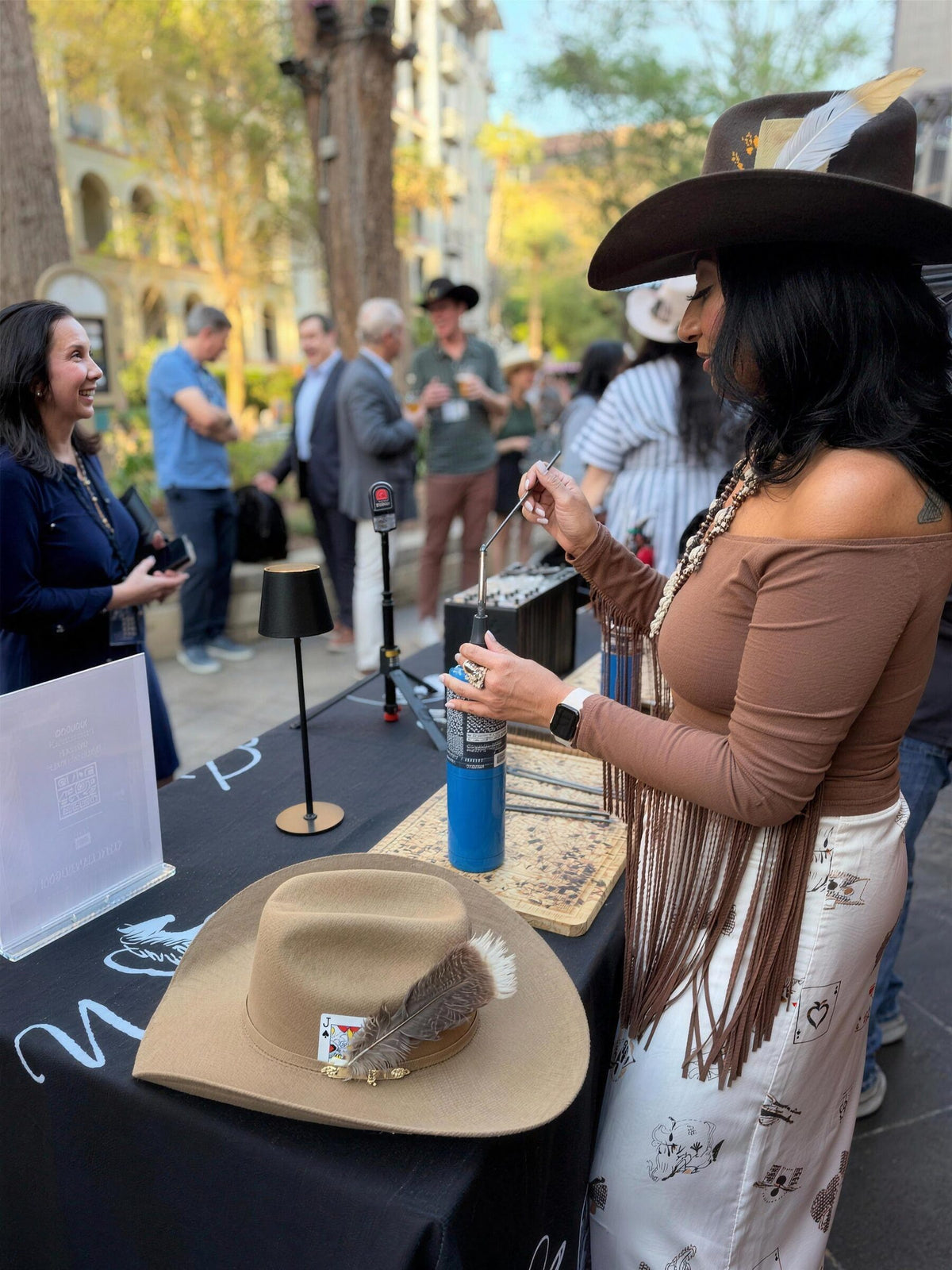 Wild Pony stylist using a heated tool to add a custom design to a guest's cowboy hat