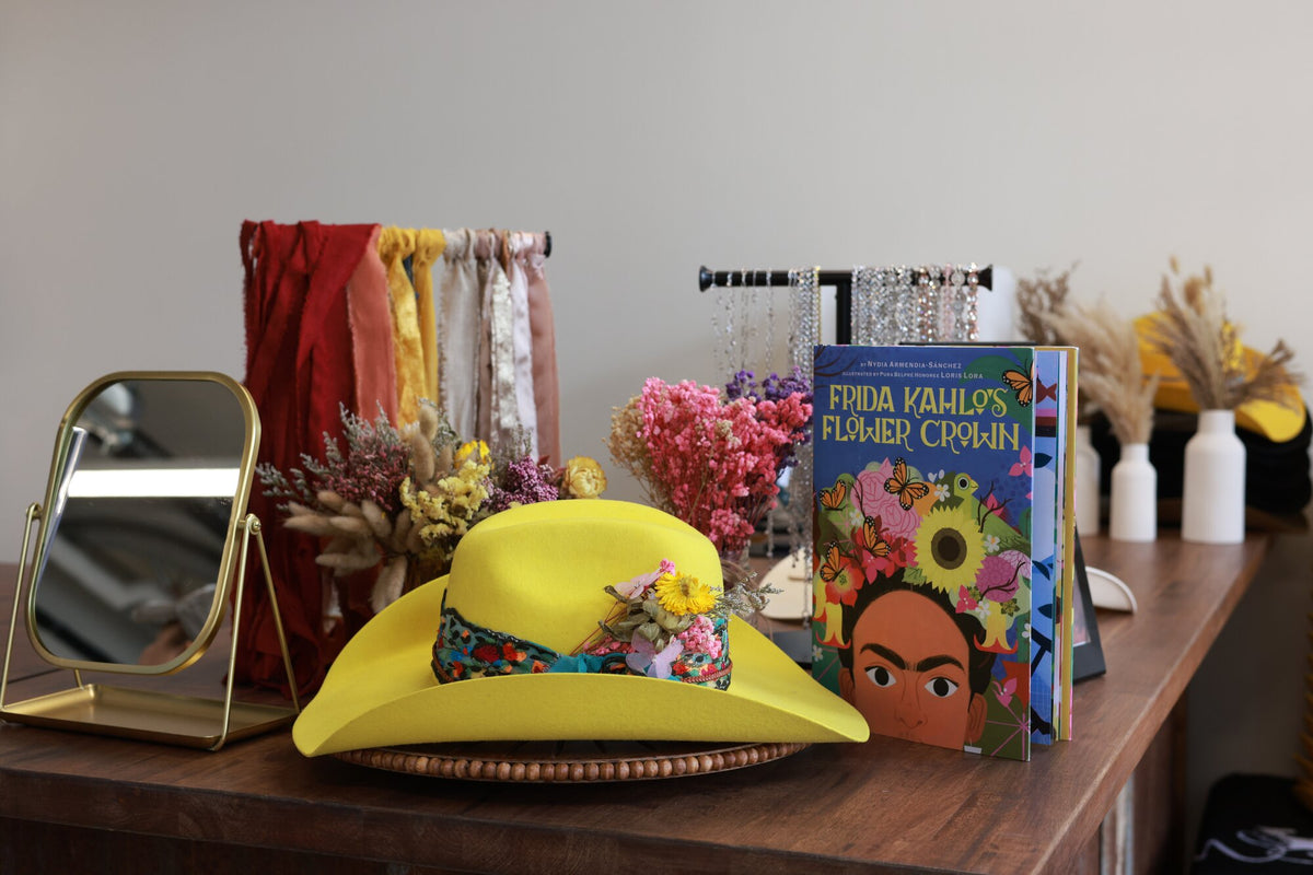 Close styling of a yellow custom felt hat with a floral band and the Frida Kahlo book at Wild Pony Basila Frocks